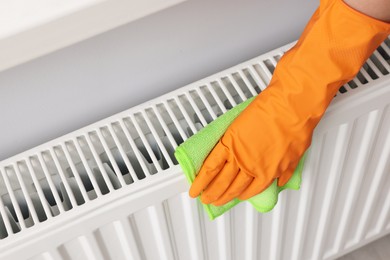 Photo of Woman cleaning white radiator with rag indoors, above view. Space for text