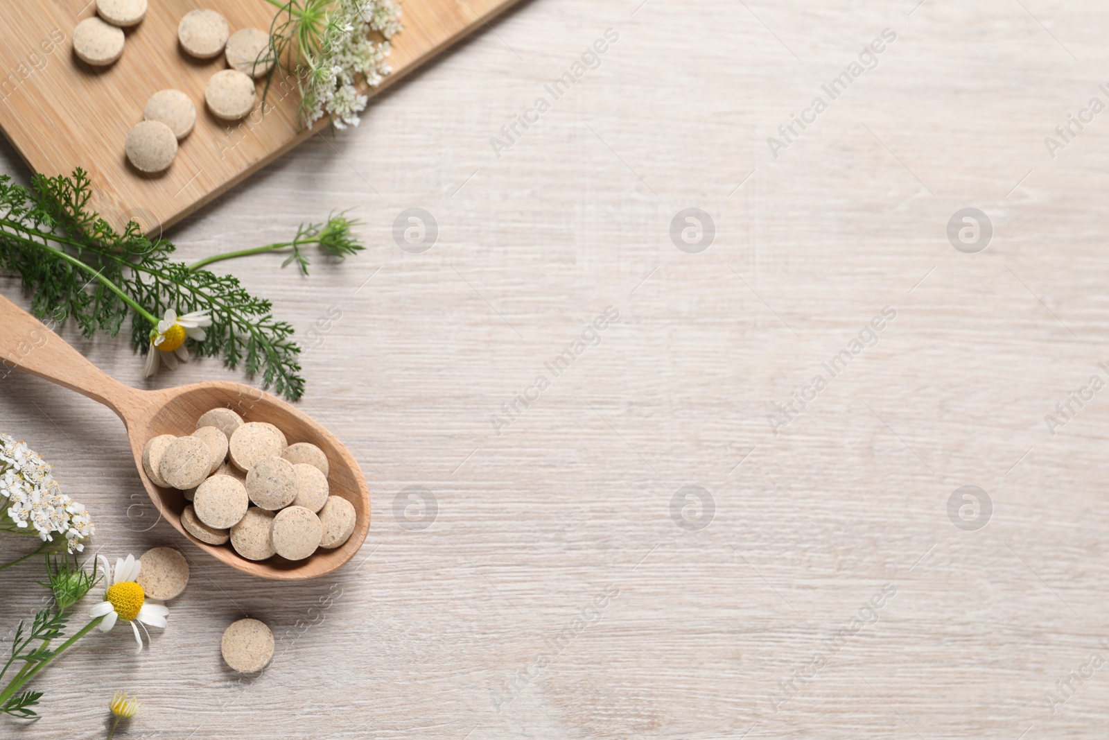 Photo of Pills, herbs and flowers on wooden table, flat lay with space for text. Dietary supplements