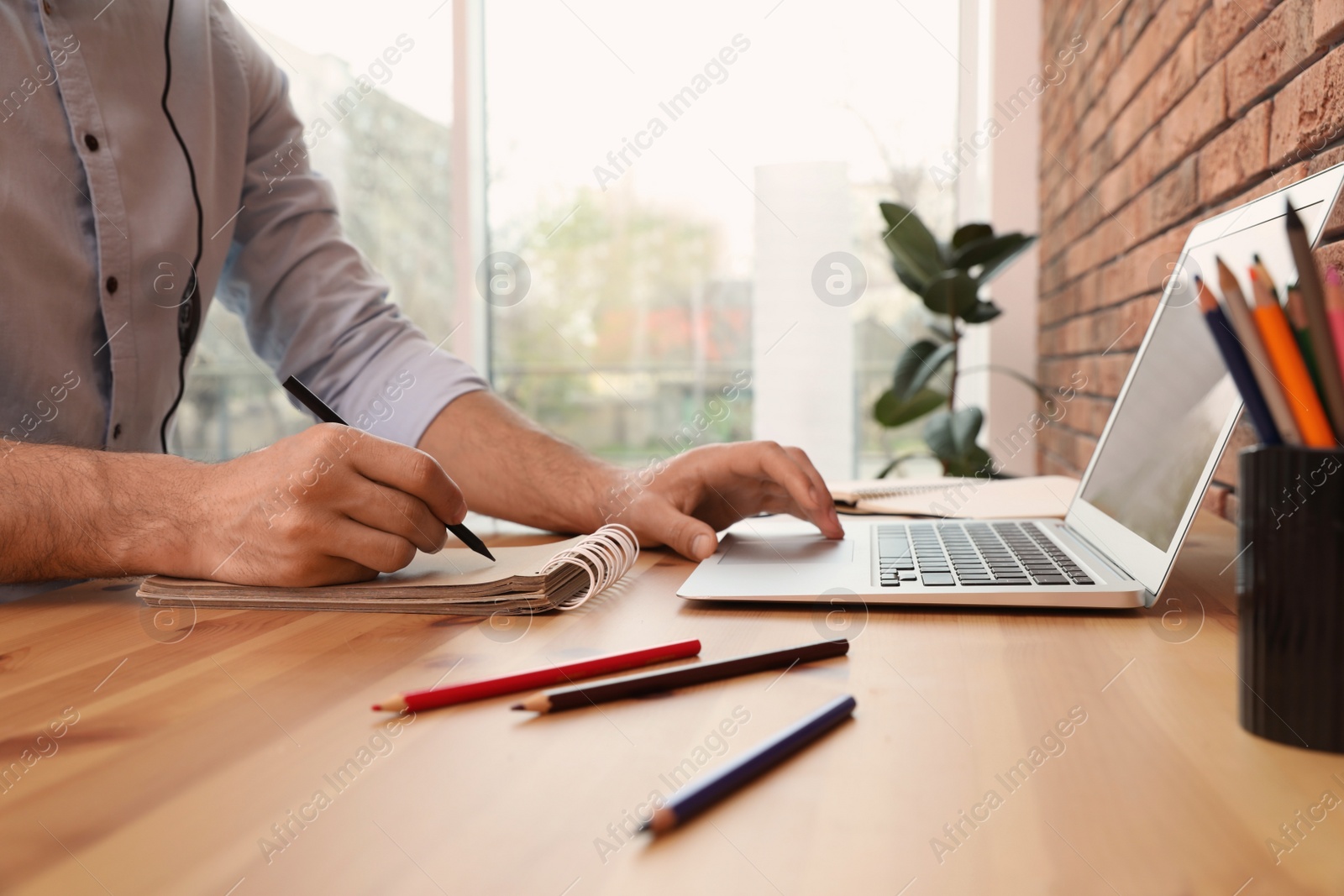 Photo of Man drawing in notebook at online lesson indoors, closeup. Distance learning