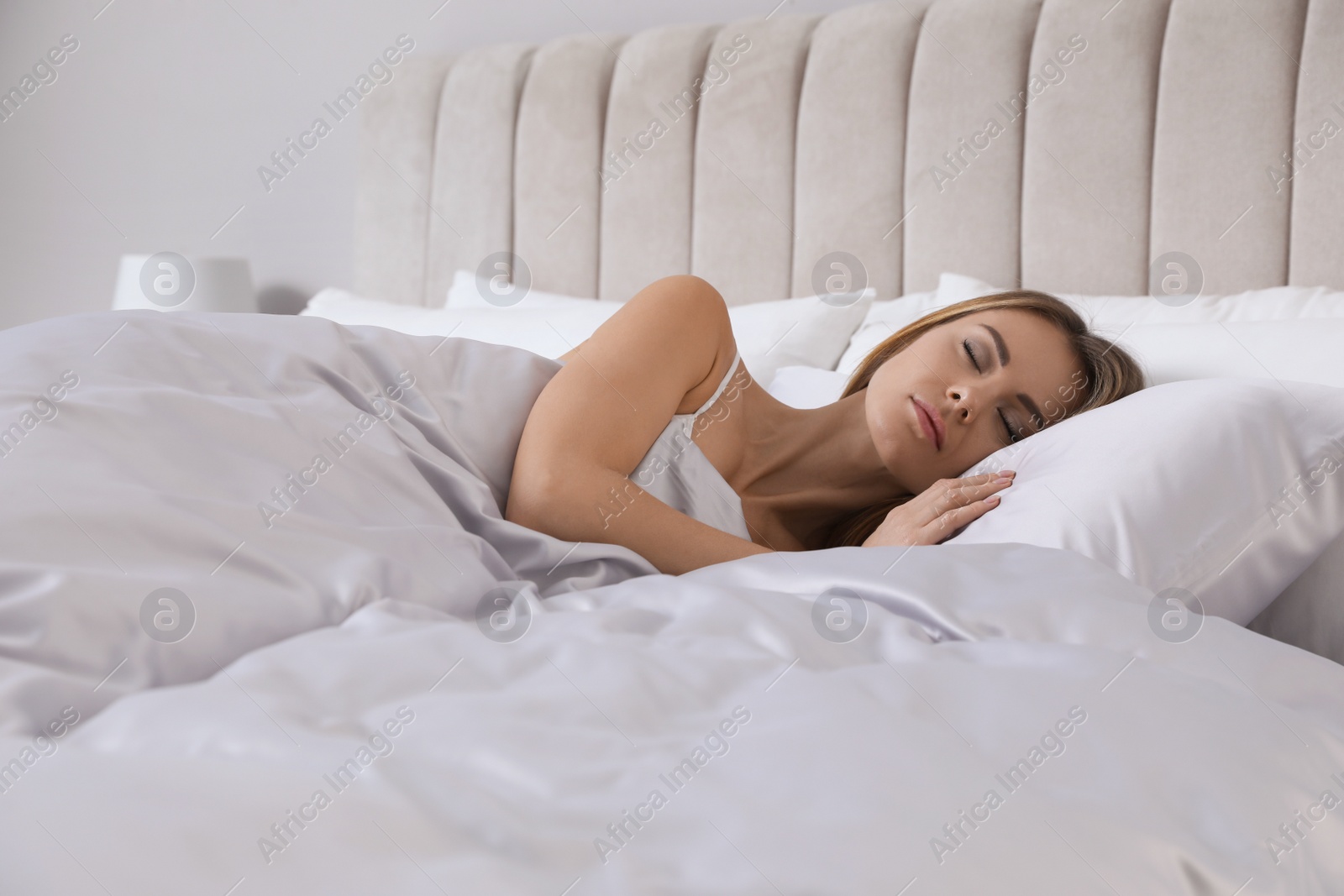 Photo of Beautiful woman sleeping in comfortable bed with silky linens