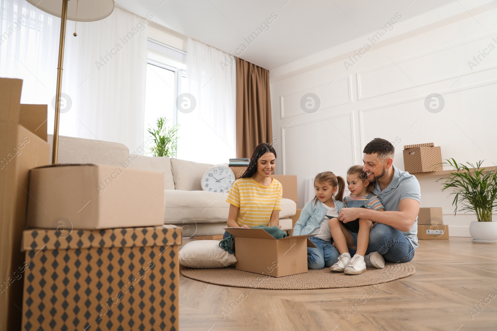 Photo of Happy family unpacking moving box at their new house