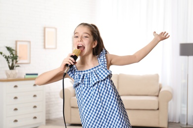 Cute girl singing in microphone at home