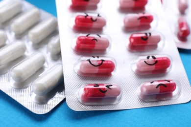 Photo of Different antidepressants with emoticons on light blue background, closeup