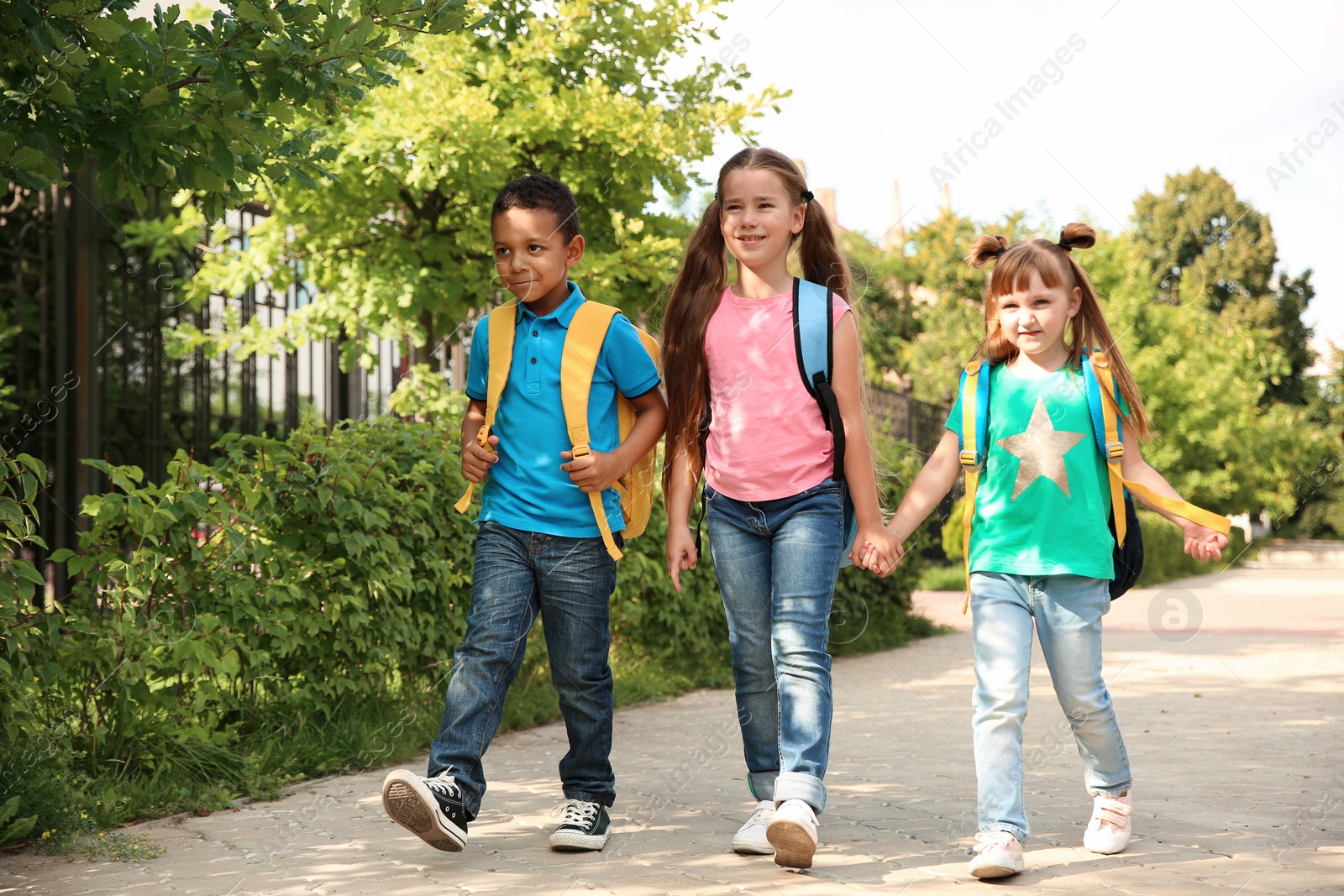 Photo of Cute little children with backpacks going to school