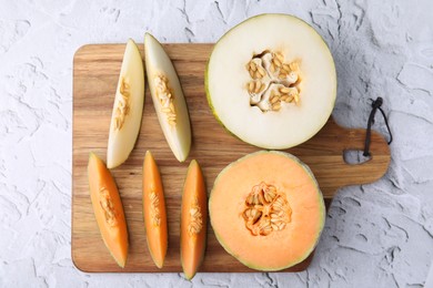 Photo of Tasty colorful ripe melons on white textured background, top view