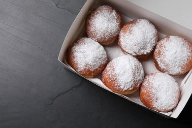 Photo of Delicious sweet buns in box on dark gray table, top view. Space for text