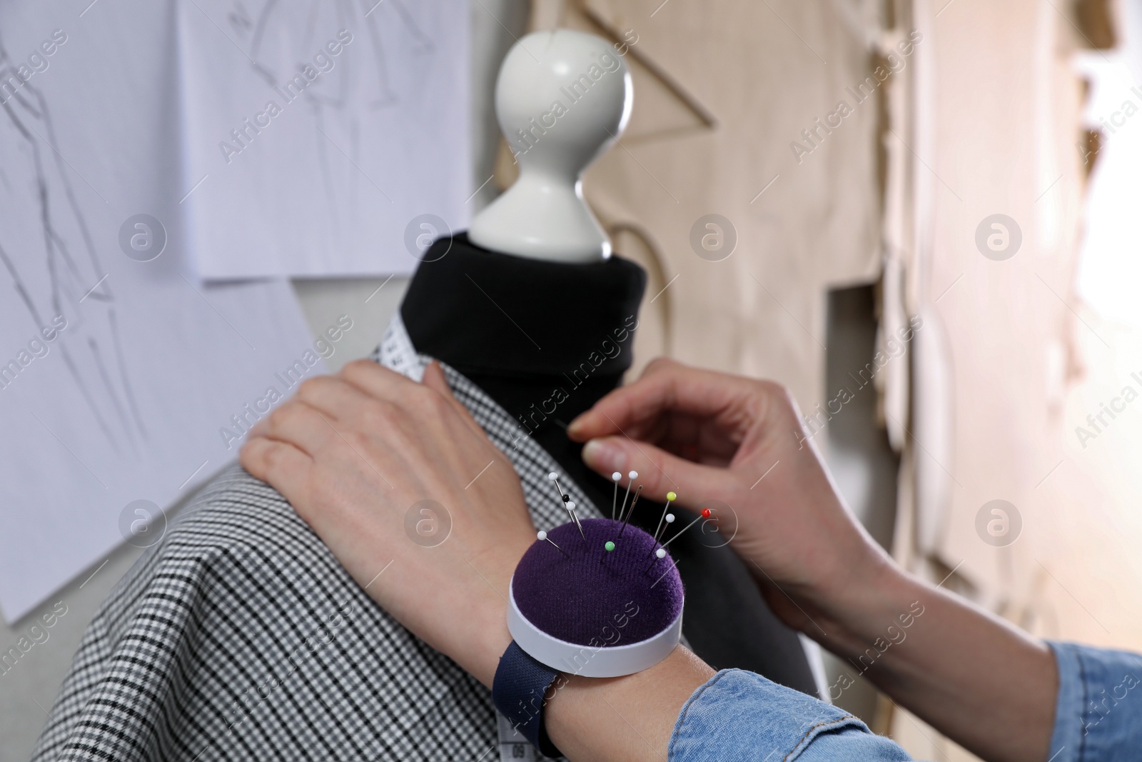 Photo of Tailor pinning fabric at mannequin in atelier, closeup