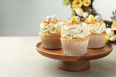 Photo of Tasty Easter cupcakes with vanilla cream on gray table, space for text