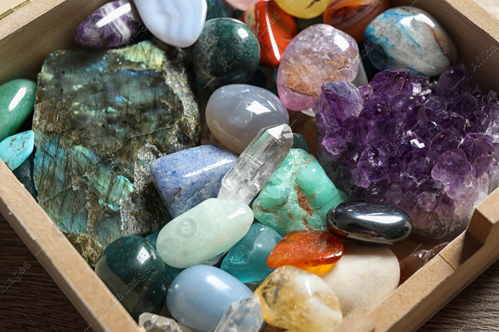 Photo of Box with different beautiful gemstones on table, closeup