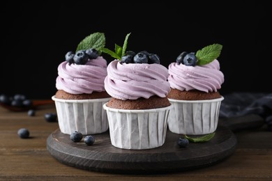 Photo of Sweet cupcakes with fresh blueberries on wooden table