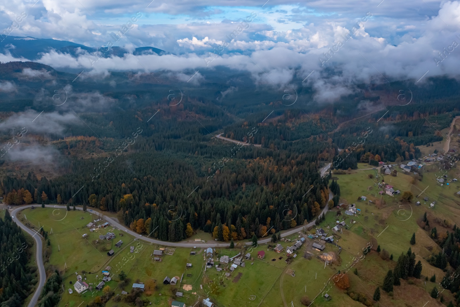 Image of Aerial view of beautiful forest, road and mountain village on autumn day