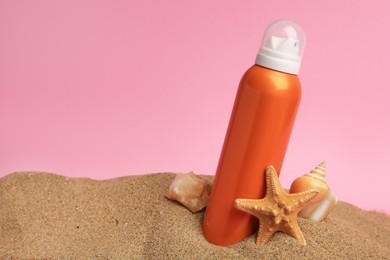 Sand with sunscreen, stone, starfish and seashell against pink background, space for text. Sun protection care