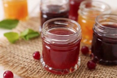Photo of Jars of different jams on table, closeup