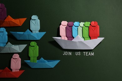Photo of Many colorful paper figures in boats and phrase Join Us Team on green background, flat lay. Recruiter searching employee