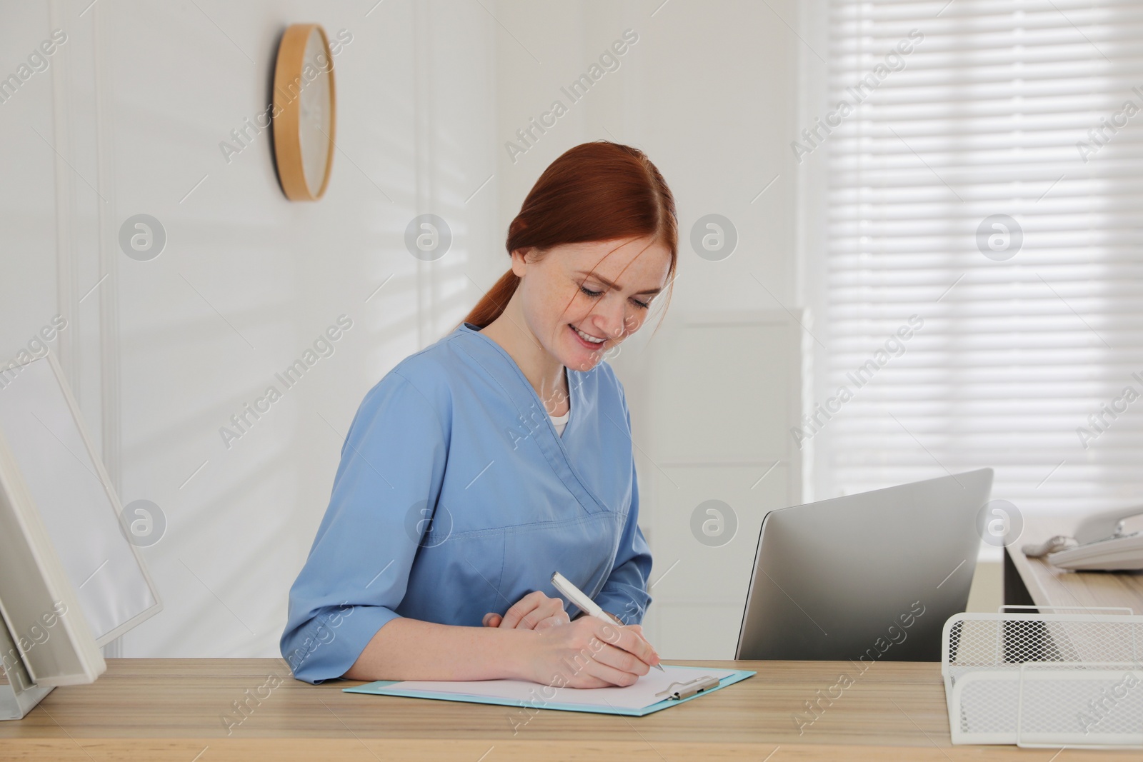 Photo of Receptionist with clipboard at countertop in hospital