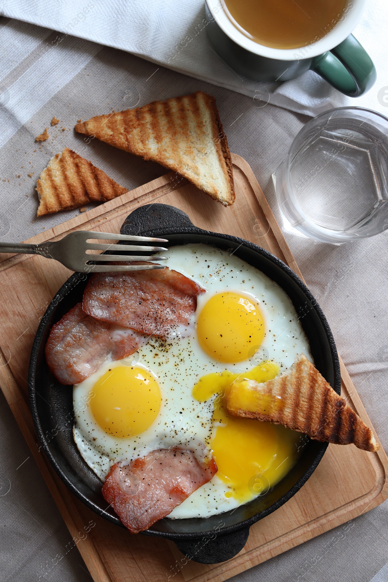 Photo of Tasty fried eggs with bacon and toasts served on table, flat lay