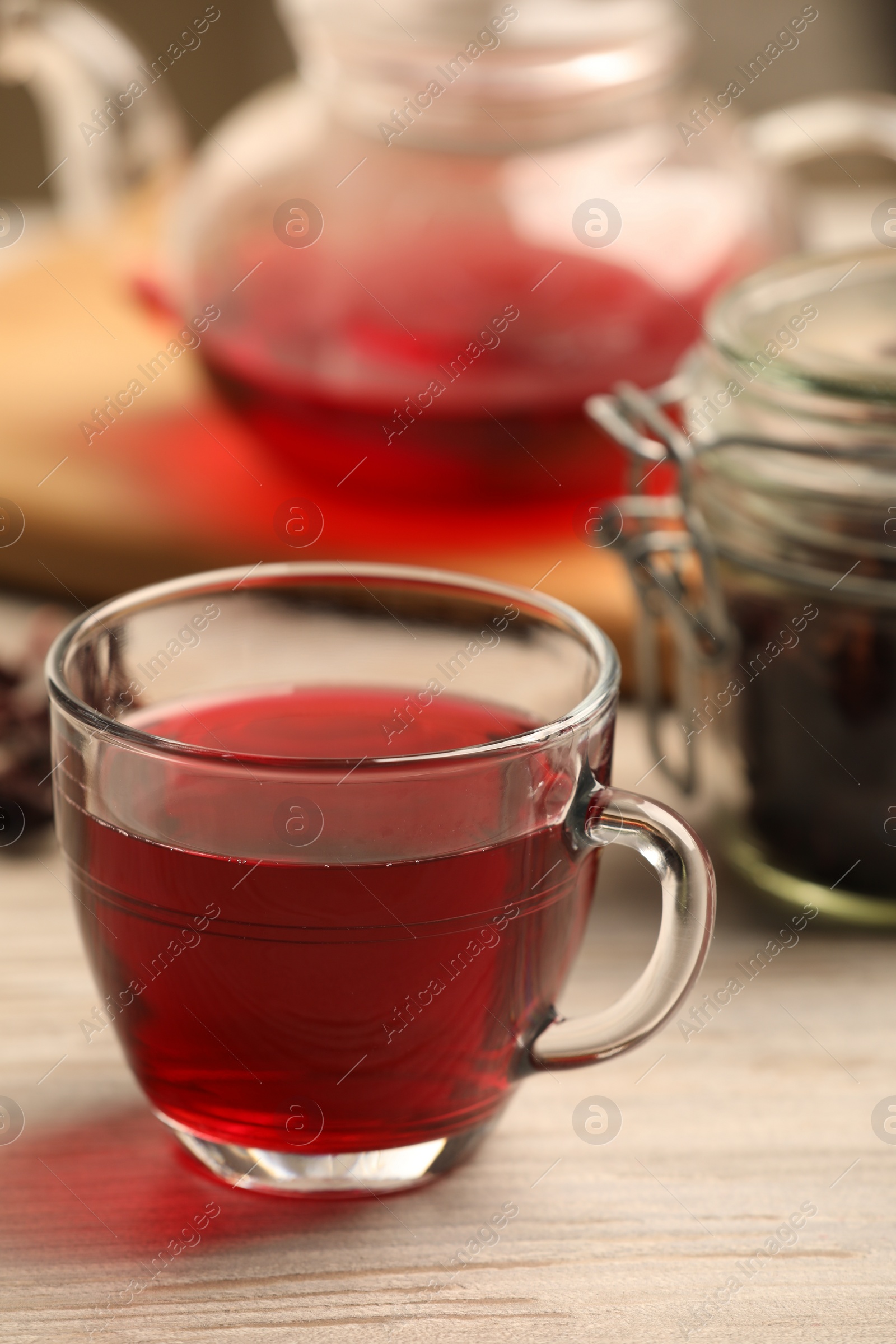 Photo of Cup of delicious hibiscus tea on white wooden table, closeup