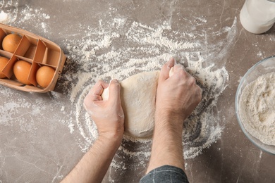 Photo of Man kneading dough for pastry on table