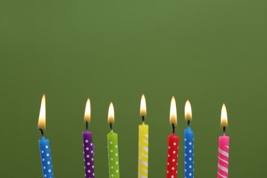 Photo of Many burning candles on green background, closeup. Birthday celebration