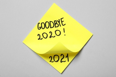 Photo of Yellow memory stickers with text Goodbye 2020 and number 2021 on light grey background, top view