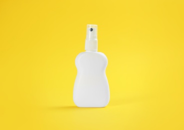 Bottle with insect repellent spray on yellow background