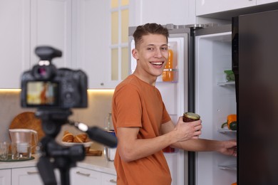 Photo of Smiling food blogger explaining something while recording video in kitchen