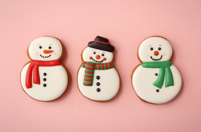 Photo of Christmas snowman shaped gingerbread cookies on pink background, flat lay