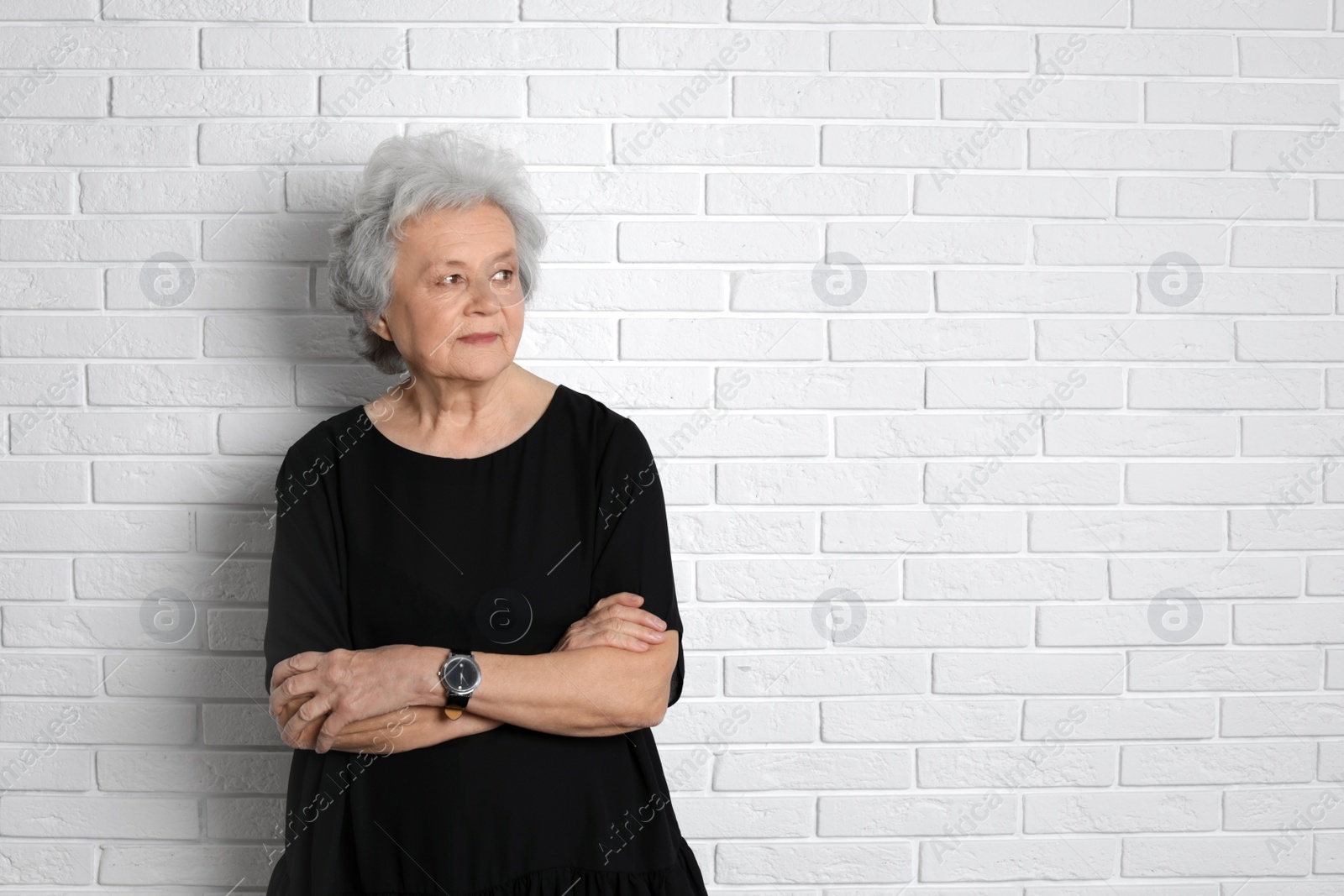 Photo of Portrait of mature woman near brick wall. Space for text