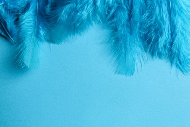Photo of Beautiful feathers on light blue background, flat lay. Space for text