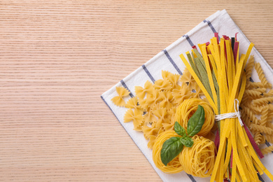 Different types of pasta on wooden table, top view. Space for text