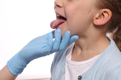 Photo of Doctor examining girl`s oral cavity on white background, closeup