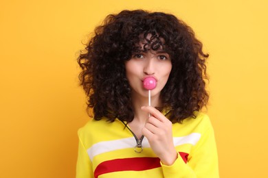 Beautiful woman with lollipop on yellow background