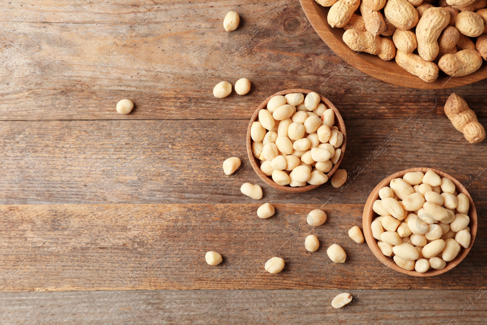 Photo of Flat lay composition with peanuts and space for text on wooden table