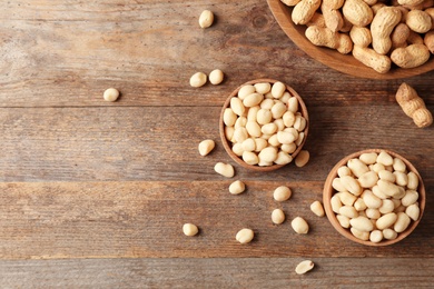 Photo of Flat lay composition with peanuts and space for text on wooden table