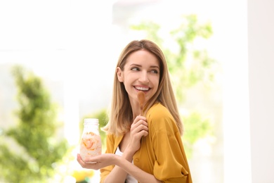 Photo of Young attractive woman eating tasty yogurt, indoors