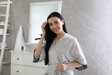 Photo of Beautiful young woman wearing silk robe in bathroom