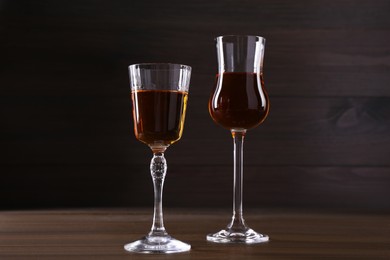 Photo of Different delicious liqueurs in glasses on wooden table