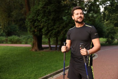 Man practicing Nordic walking with poles outdoors. Space for text