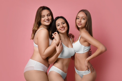 Group of women with different body types in underwear on pink background