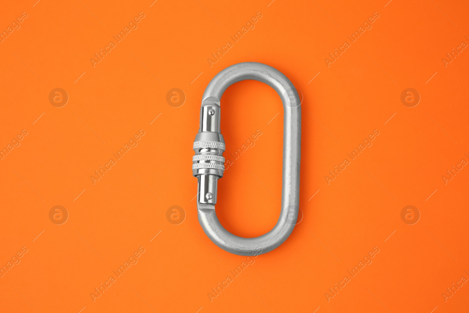 Photo of One metal carabiner on orange background, top view