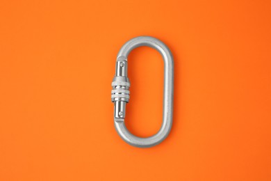Photo of One metal carabiner on orange background, top view