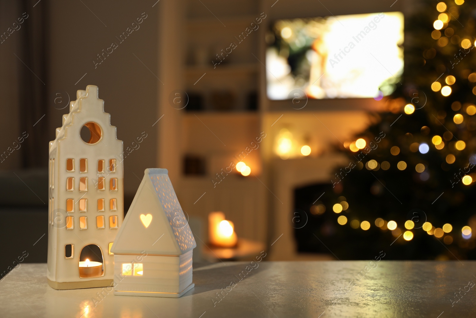 Photo of Beautiful house shaped candle holders on table indoors, space for text. Bokeh effect