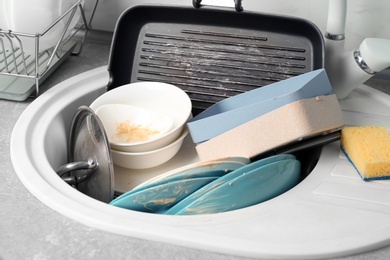 Photo of Messy pile of dirty dishes in sink