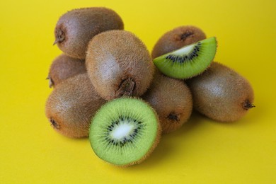 Photo of Heap of whole and cut fresh kiwis on yellow background