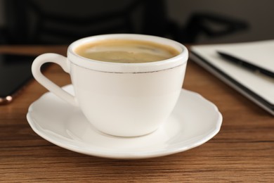 Photo of Cup of americano on wooden table in office, closeup. Coffee Break