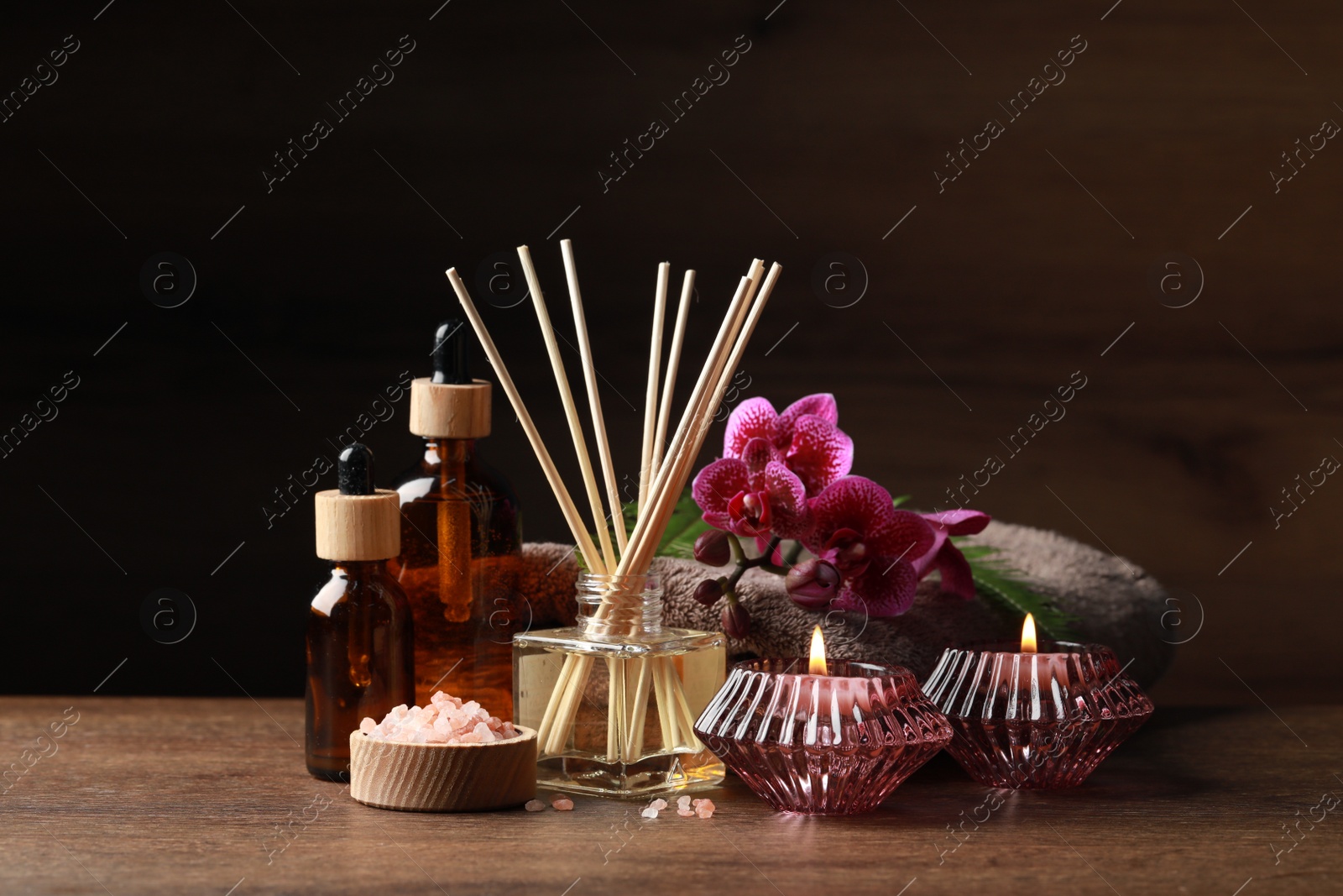 Photo of Beautiful spa composition with different care products and burning candles on wooden table