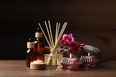 Photo of Beautiful spa composition with different care products and burning candles on wooden table