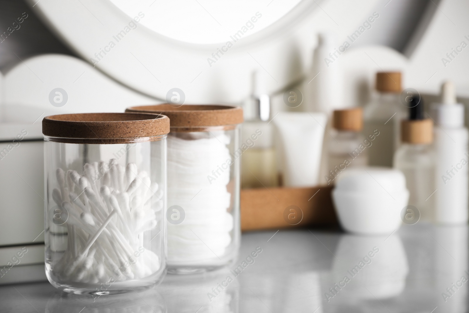 Photo of Glass jars with cotton pads and swabs on dressing table. Space for text