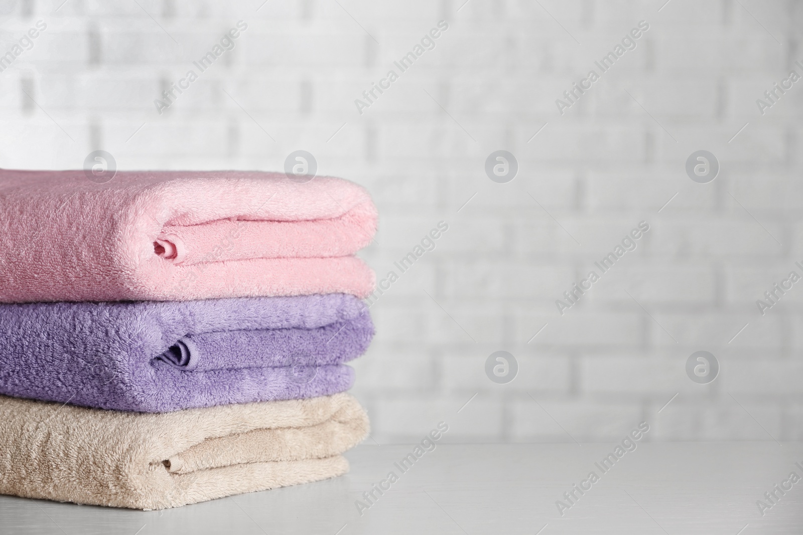 Photo of Stack of clean bath towels on white wooden table. Space for text