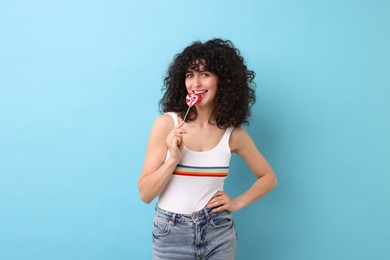 Beautiful woman with lollipop on light blue background